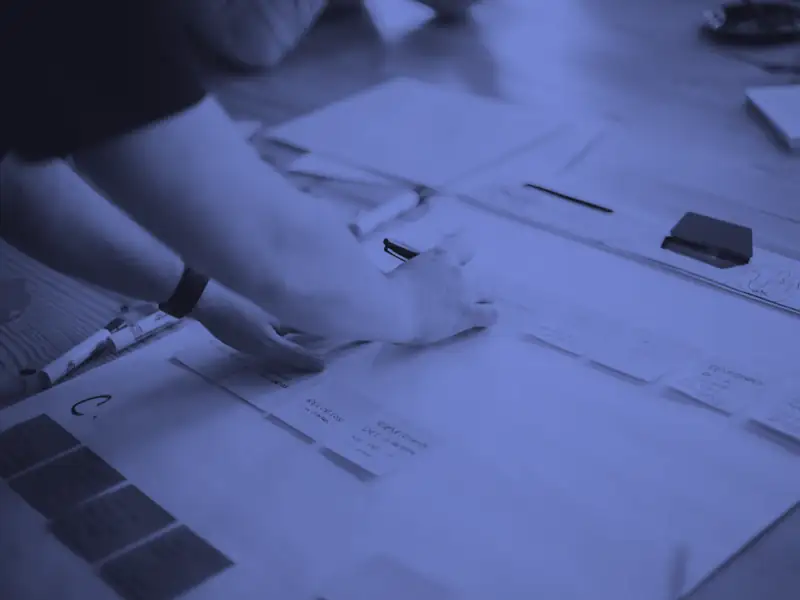 Mãos organizando as etapas de um processo em post-its sobre uma folha na mesa